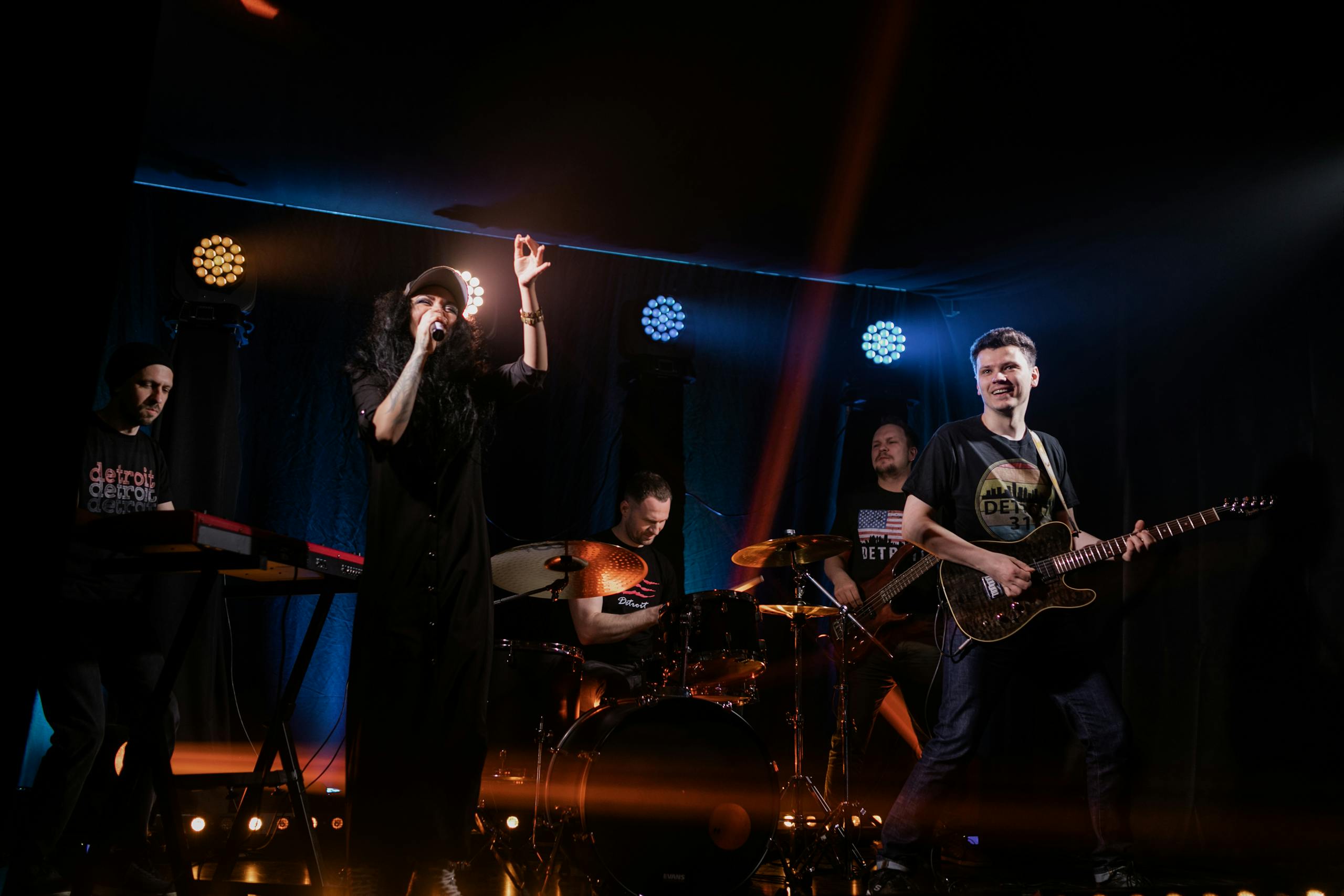 Dynamic live music performance featuring a rock band with singer and instruments on stage.