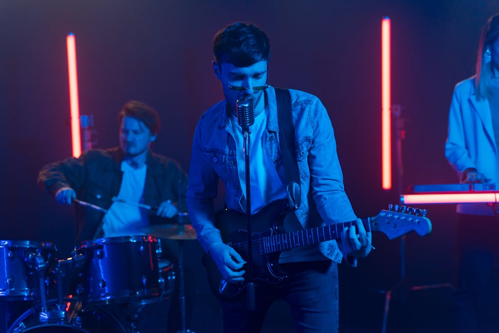Dynamic performance by a band with guitarist, drummer, and neon lights setting the stage.