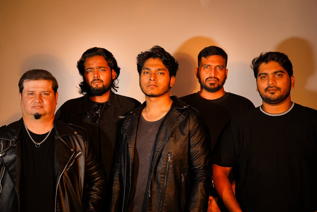 Dynamic portrait of a rock band posing with confident expressions in a studio environment.