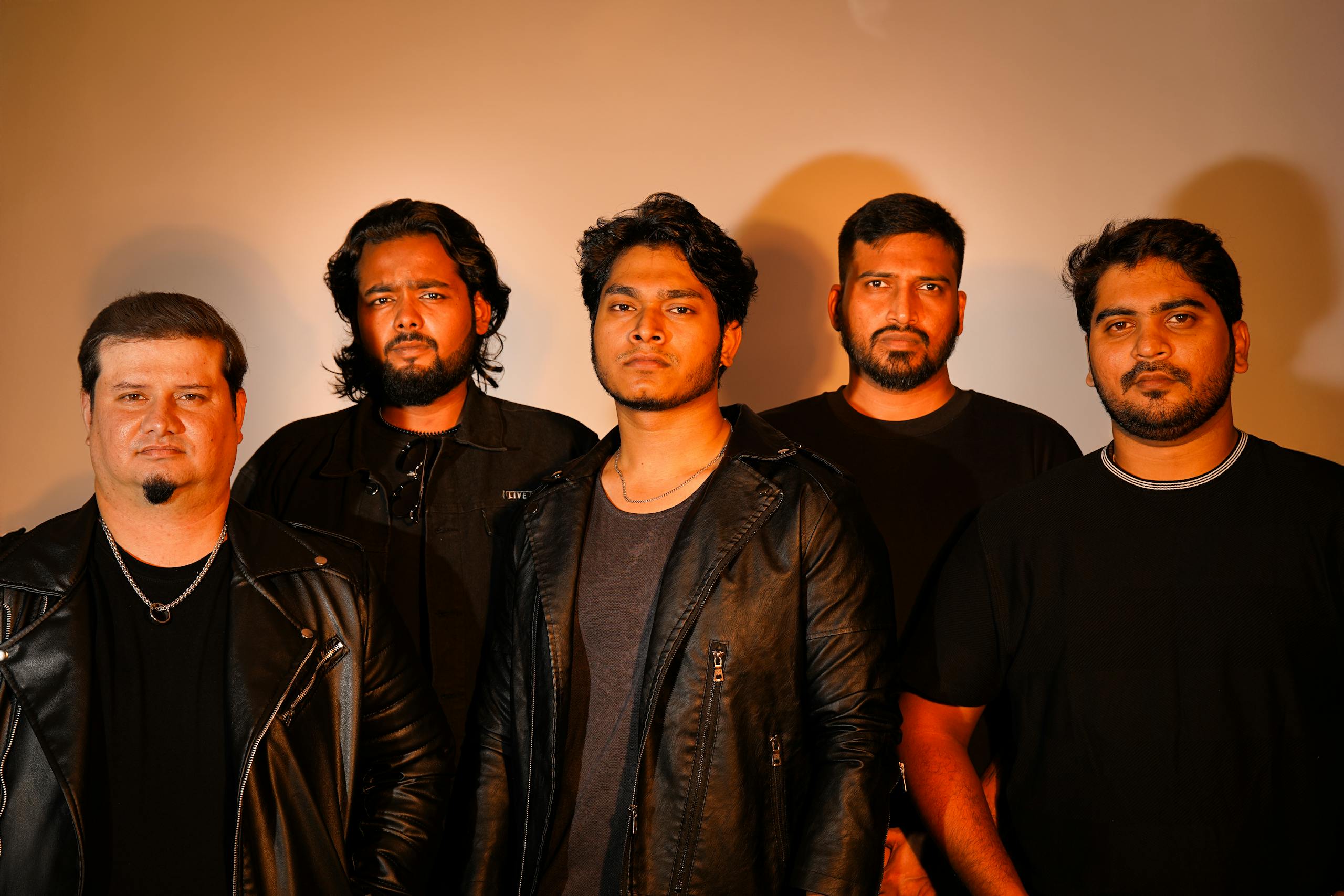 Dynamic portrait of a rock band posing with confident expressions in a studio environment.